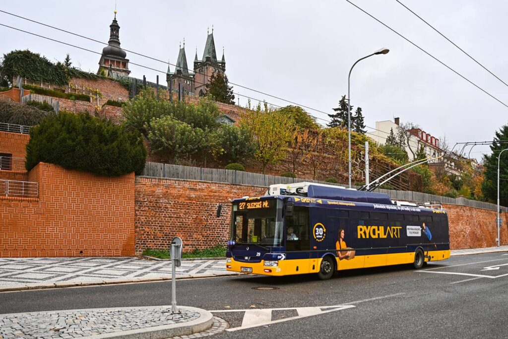 Trolejbus polepený reklamou Rychlart projíždějící pod Zpívajícími schody
