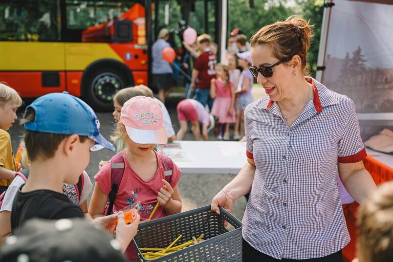 Zaměstnankyně z marketingového oddělení rozdává dětem upomínkové předměty