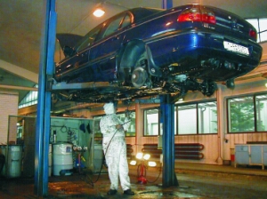 Servis vozidel - zvednuté auto na ramenech při nástřiku podvozku