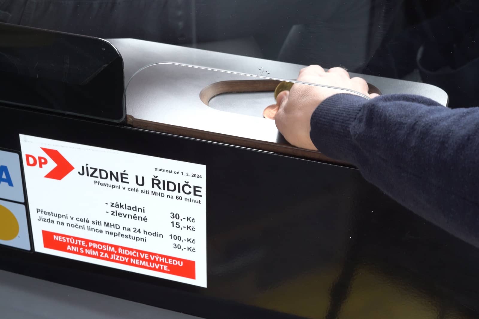 A passenger's hand gives the driver change when buying a ticket