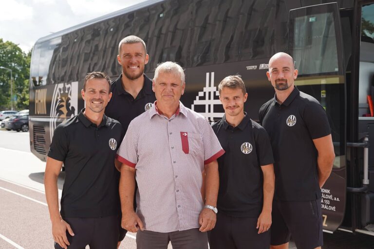 Řidič zájezdové dopravy ve společnosti prvoligových fotbalistů před fotbalovým autobusem