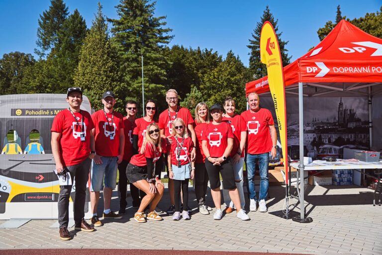 Zaměstnanci v červených tričkách dopravního podniku u propagačního stánku